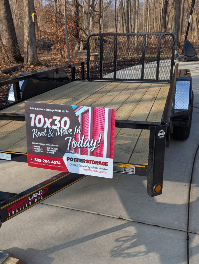 Slightly offset front view of a brand-new 6.5' by 14' tandem axle trailer with wood plank floor and 7000lb capacity at Potter Storage in Morton, IL.